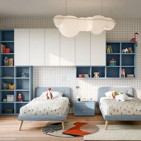 Twin-bed kids' room with matching blue upholstered beds, blue-and-white cubby shelving styled with books and toys, and a