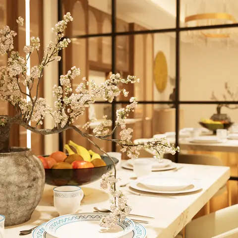 Marble dining table set with blue-and-white china and a large cherry-blossom branch centerpiece, reflected in a black-grid