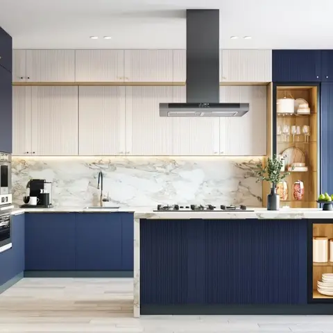 Kitchen with navy blue and cream fluted cabinetry, a marble waterfall-edge island, gold trim accents, and a built-in