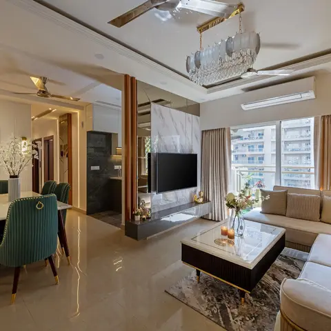 Open-plan dining and living area with a marble-top dining table and brass-studded emerald velvet chairs on one side, and an