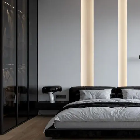 Bedroom with a low black upholstered bed, a smoked-glass walk-in wardrobe, and twin vertical LED light strips washing the