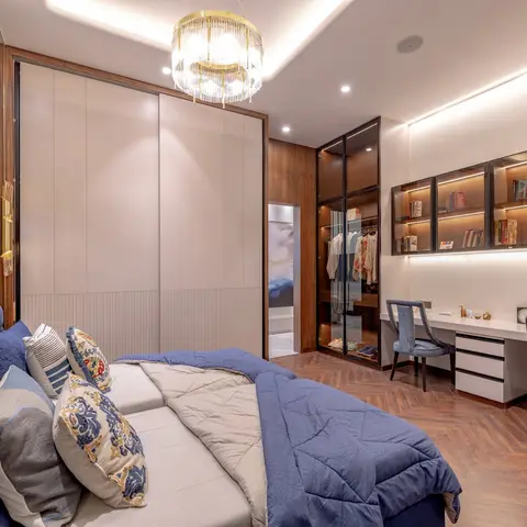 Bedroom with a blue tufted velvet headboard, a gold multi-tier chandelier, a glass-front walk-in wardrobe, and a herringbone